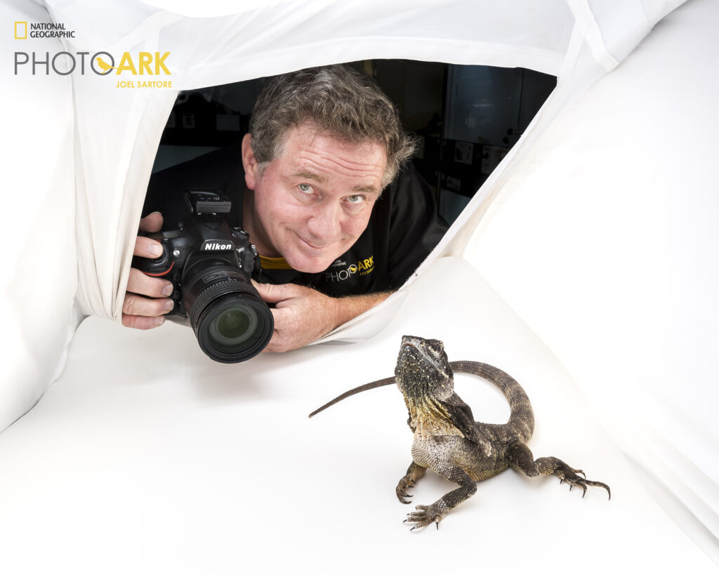 Man posing next to a lizard while holding a camera